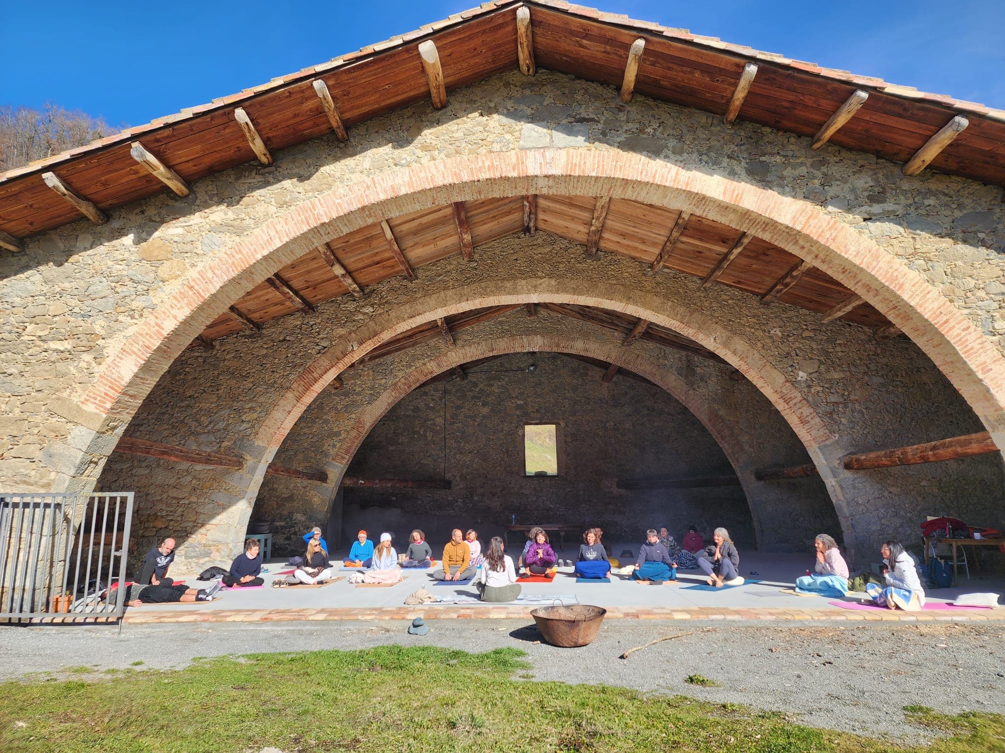 Grupo de meditación bajo el arco de piedra de Mas Besaura